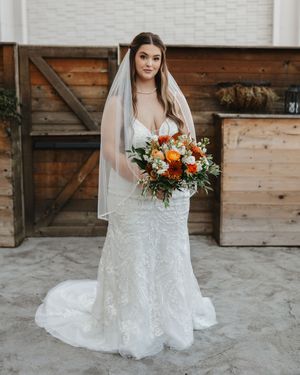 Beautiful bridal portraits showing details of a white lace wedding gown with orange floral bouquet.