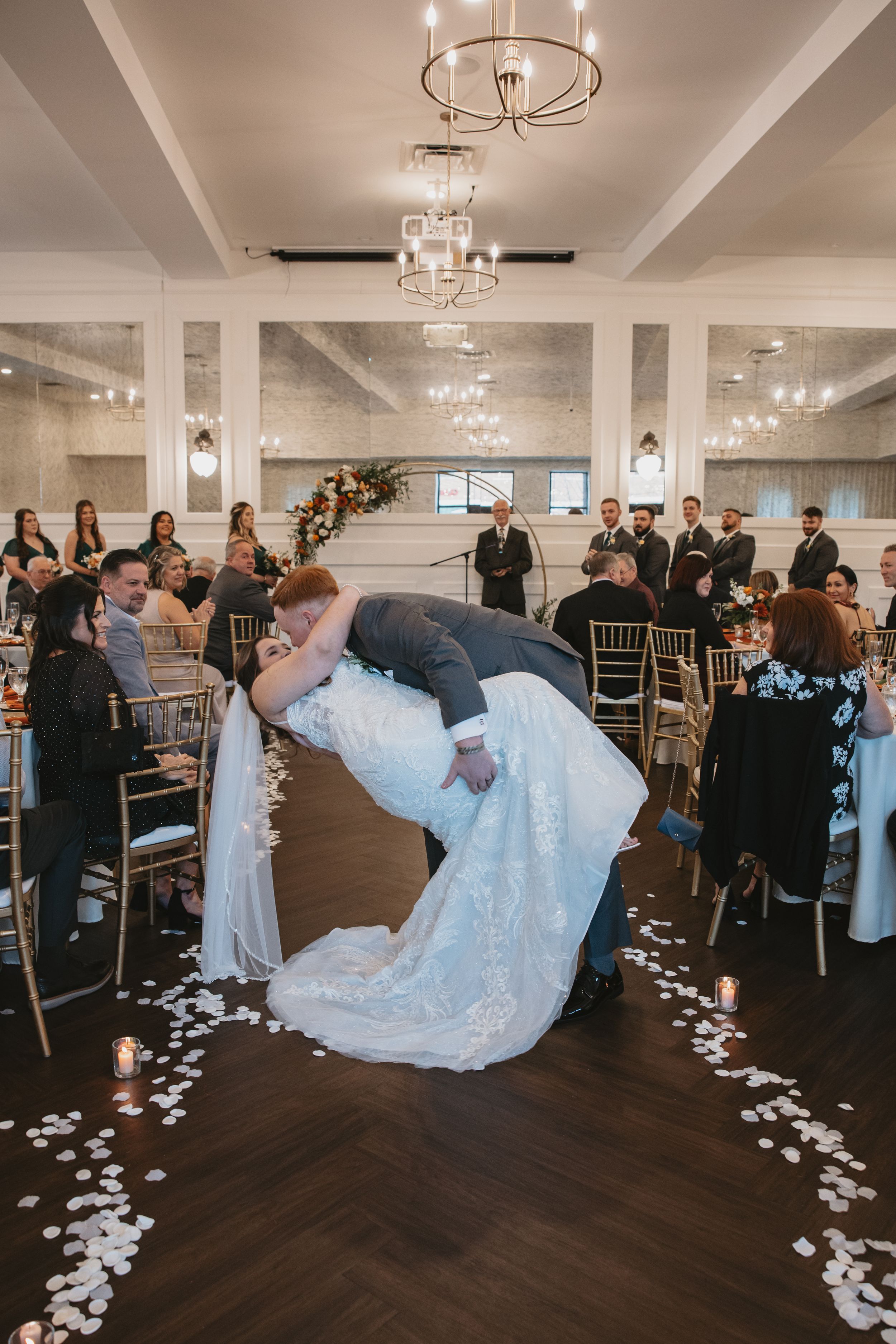 A sequence of photos showing a bride dipping during a romantic first dance in an elegant ballroom with chandeliers.