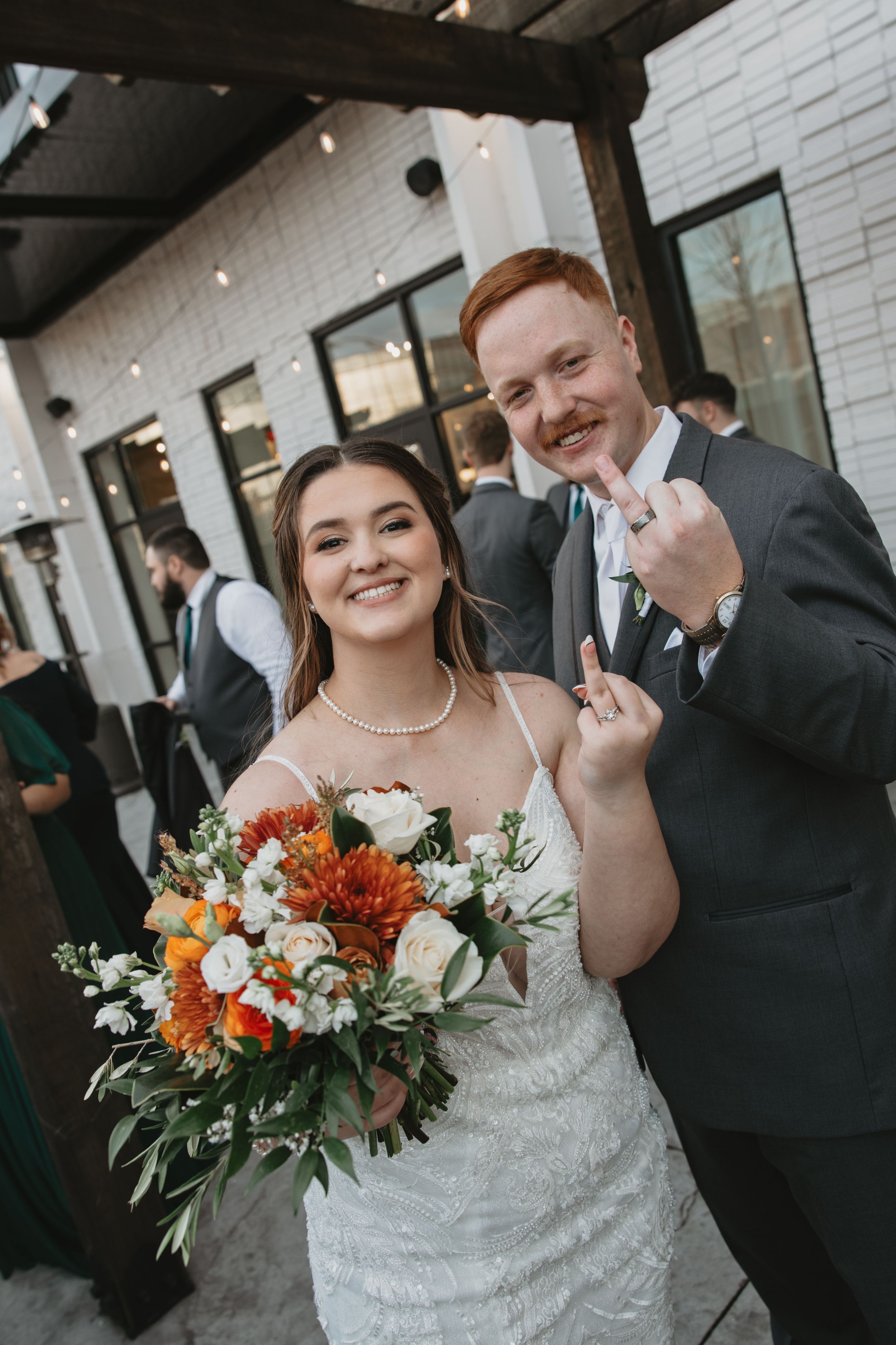 Wedding celebration at modern venue with white brick walls and hanging string lights.