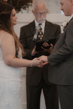 Wedding ceremony moments during ring exchange with officiant.