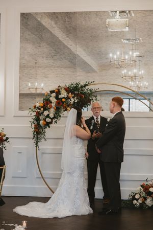 Wedding ceremony setup with floral arch and elegant white interior decor.