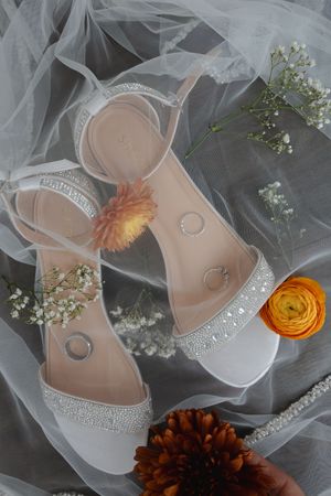 Bridal shoes and wedding rings styled with tulle veil and autumn flowers.