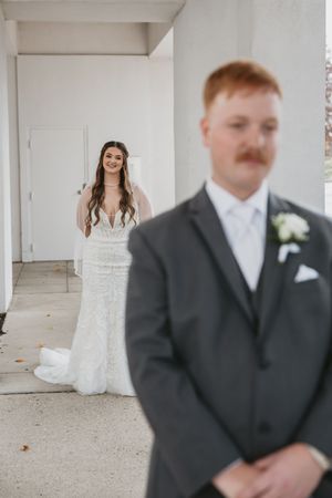 First look wedding moment captured in bright white industrial venue space.