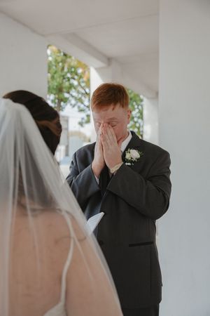 Emotional first look moment during wedding ceremony in white interior space.