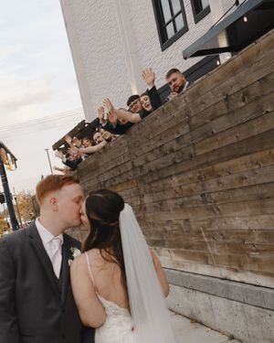 Wedding couple shares intimate moments against a rustic stone wall backdrop.