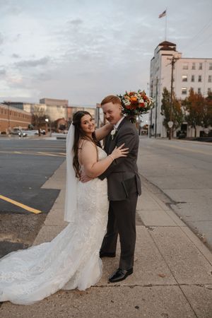 A couple shares intimate moments on a city sidewalk during their wedding photoshoot.