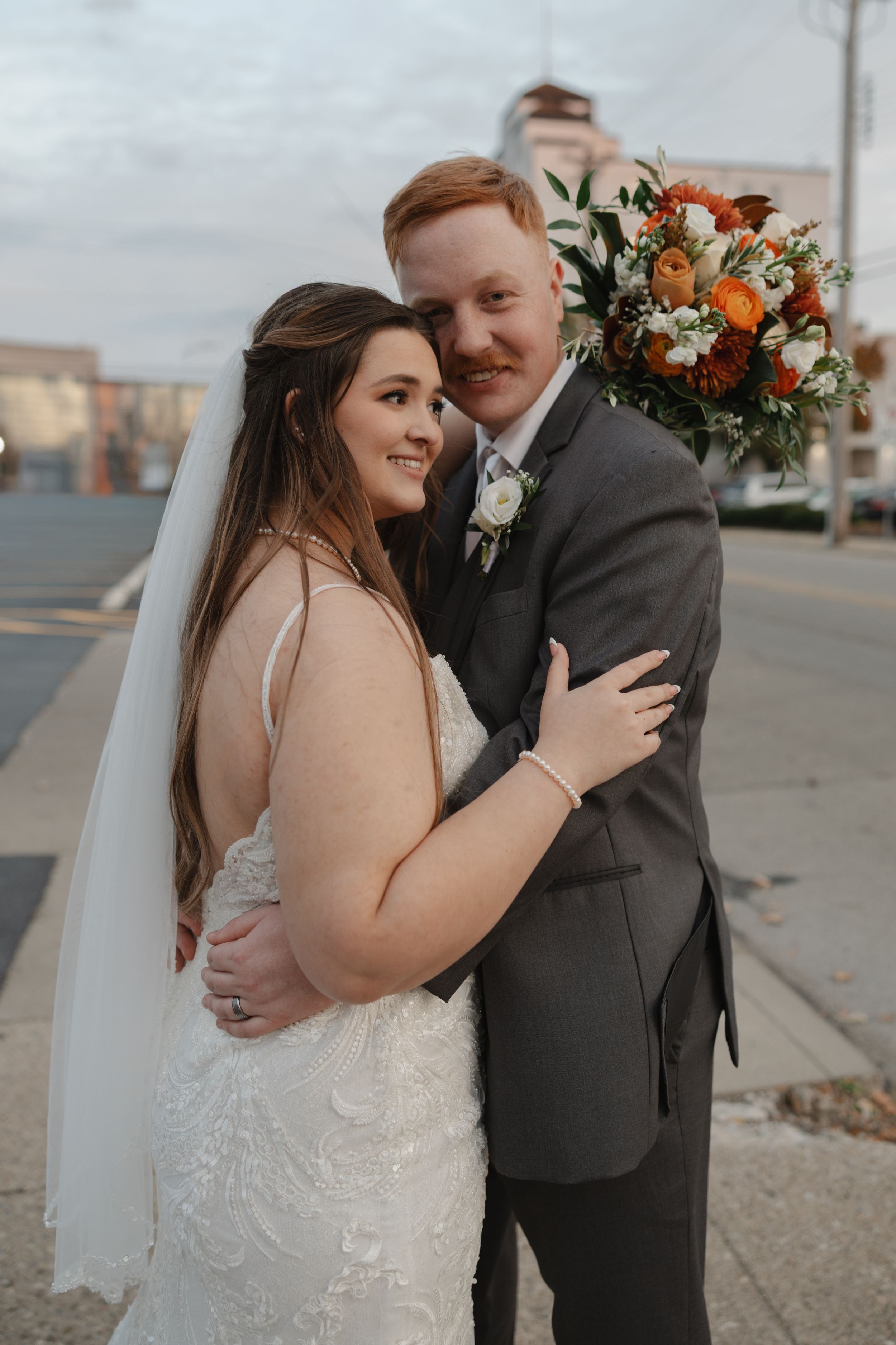 A romantic wedding photo series showing tender moments between newlyweds with orange and white floral bouquet details.