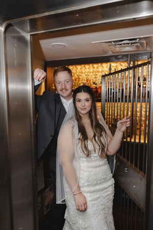Bride in white dress walking through a modern hallway with elegant lighting.