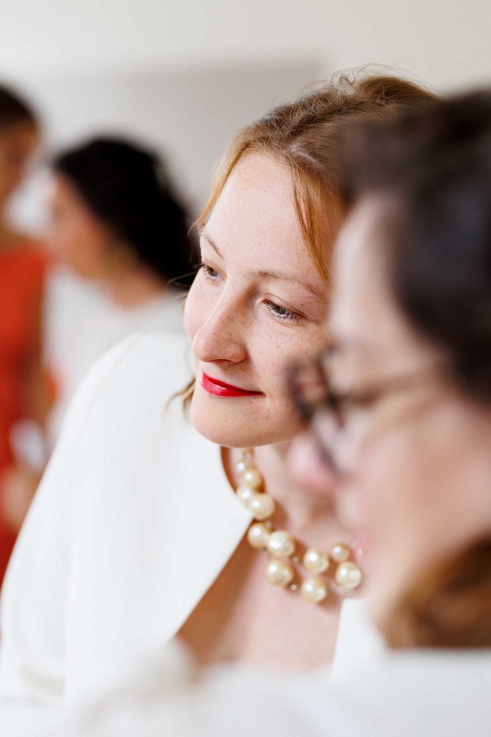 A series of profile shots showing someone with red lipstick and pearl earrings in soft lighting.