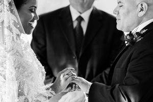 Black and white photograph of a couple in formal wedding attire during their ceremony.