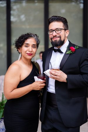 Couple in formal black attire sharing an intimate moment during a wedding photoshoot.