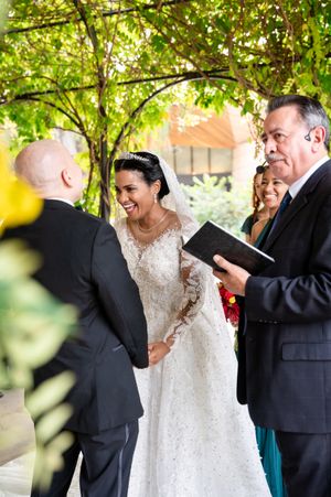 Wedding celebration outdoors with people in formal attire sharing joyful moments under green trees.