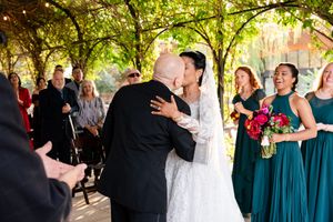 Wedding celebration in a lush garden setting with guests in teal bridesmaid dresses.