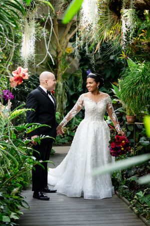 Wedding couple sharing intimate moments while walking through a tropical greenhouse garden.