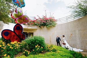 Colorful butterfly decorations adorn a garden wall with blooming pink bougainvillea flowers.