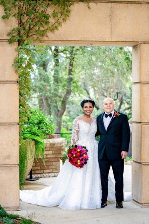 Outdoor wedding venue with stone columns and green foliage creating an elegant archway.
