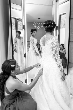 Black and white photo of someone browsing through wedding dresses in a bridal boutique.