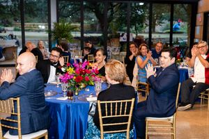 Wedding reception tables decorated with blue linens and floral centerpieces in an elegant indoor venue.