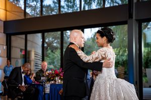 Wedding reception venue with floor-to-ceiling windows, chiavari chairs, and floral centerpieces.