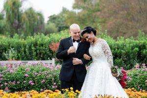 A couple shares a joyful moment together in a garden filled with colorful roses and marigolds.