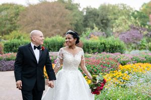 Elegant wedding couple walking through a vibrant garden filled with colorful wildflowers.