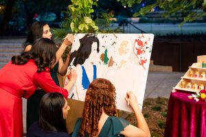 Wedding guests participating in an interactive painting activity at reception tables.