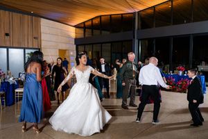 Wedding guests gather in an elegant wood-paneled venue hallway during an evening reception.