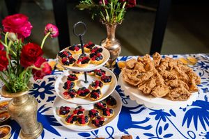 Elegant wedding reception dessert table with colorful treats on blue and white tablecloths.