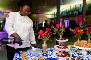 Catering staff arranges elegant appetizers and hors d'oeuvres on blue and white patterned serving platters at an event.