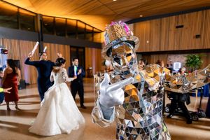 Wedding reception celebration with guests dancing in a wood-paneled venue with warm lighting.