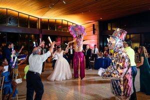 Wedding guests dance and celebrate on a warmly lit wooden dance floor during an evening reception celebration.
