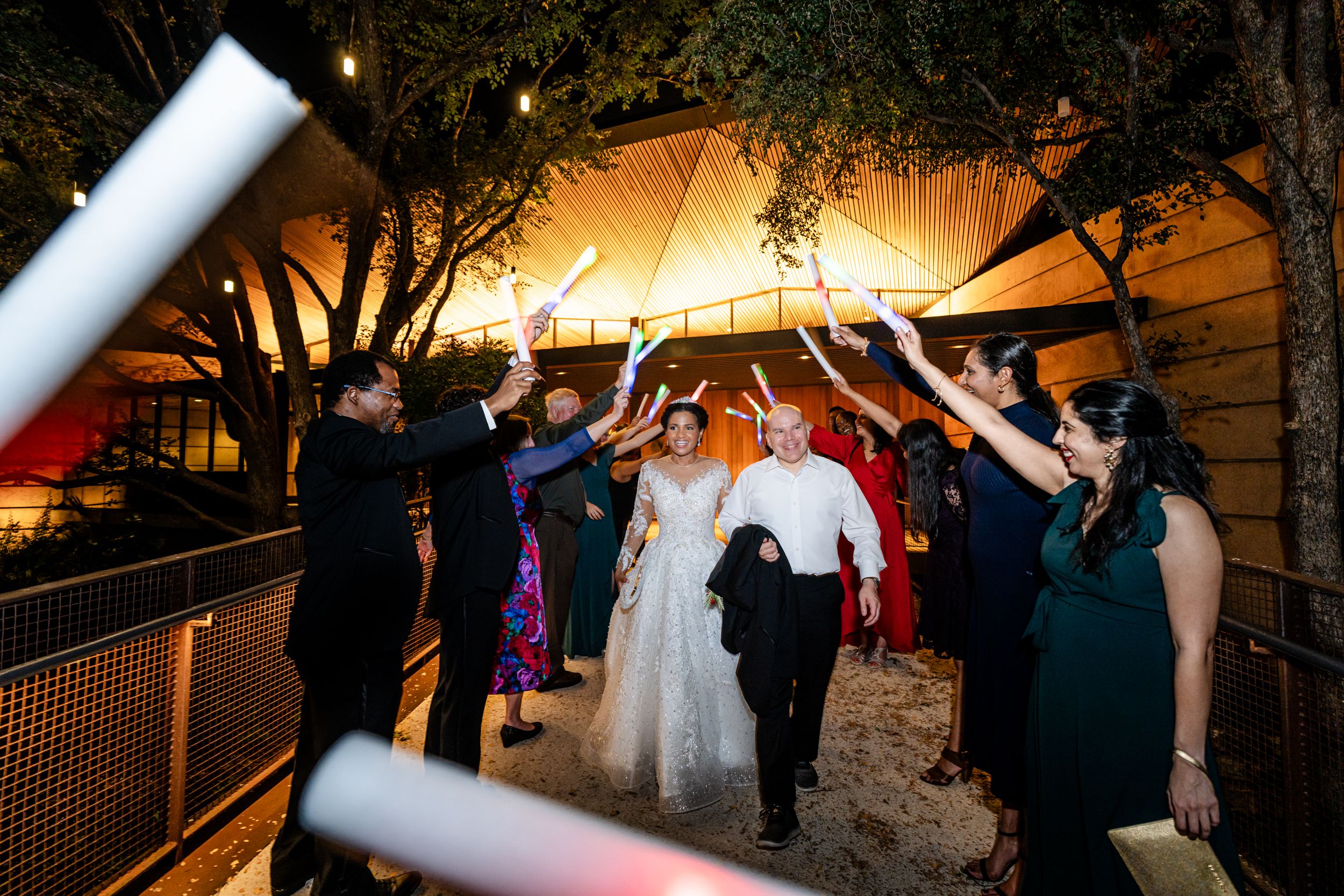 Evening wedding reception under string lights with guests mingling in an outdoor venue.