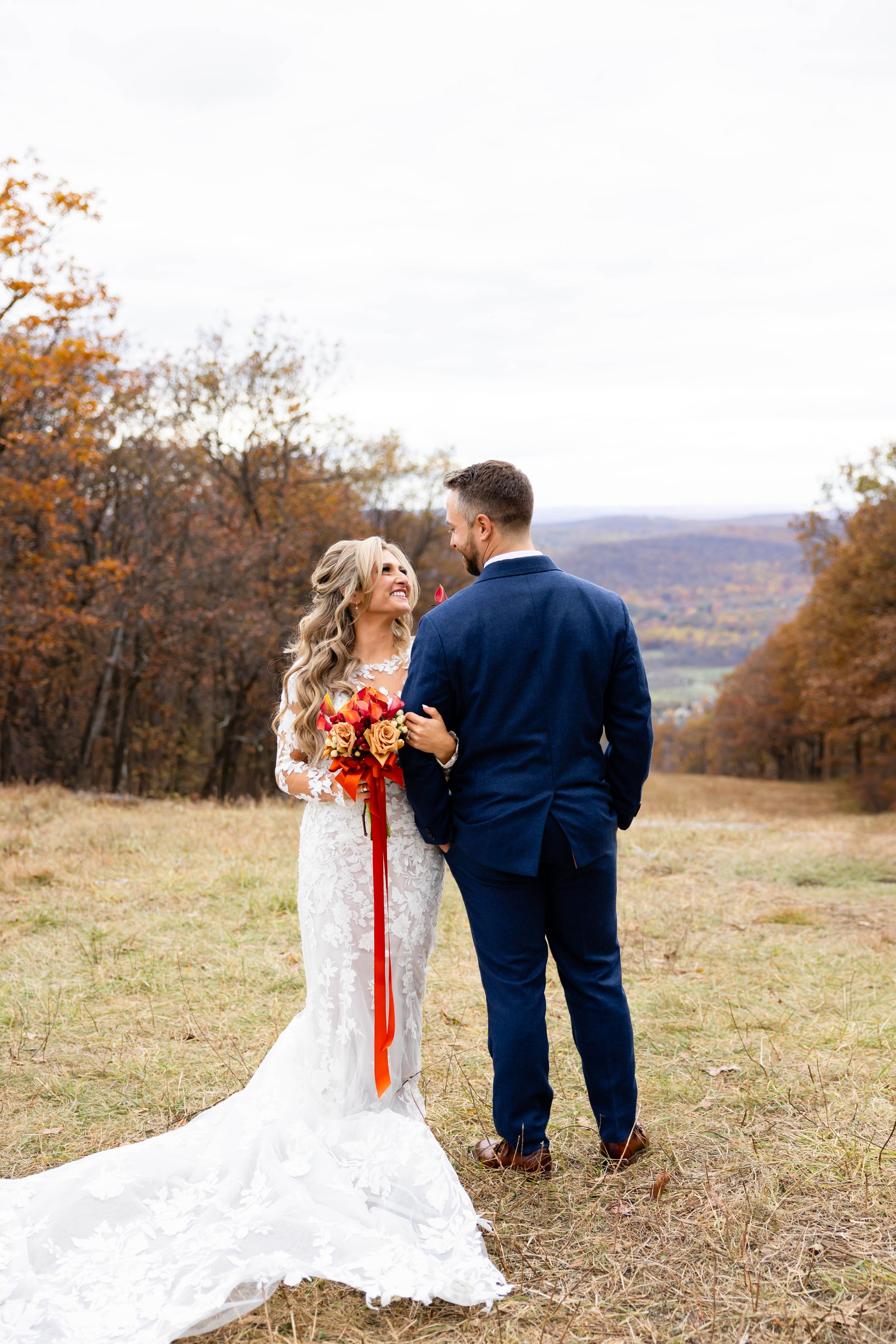 Wedding couple shares intimate moment on hilltop with autumn foliage in background. NJ wedding photographer