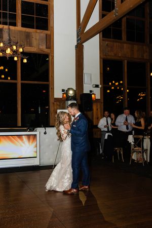 Couple shares a romantic dance in a rustic barn venue with exposed wooden beams and warm lighting. Sussex County NJ Wedding Photographer