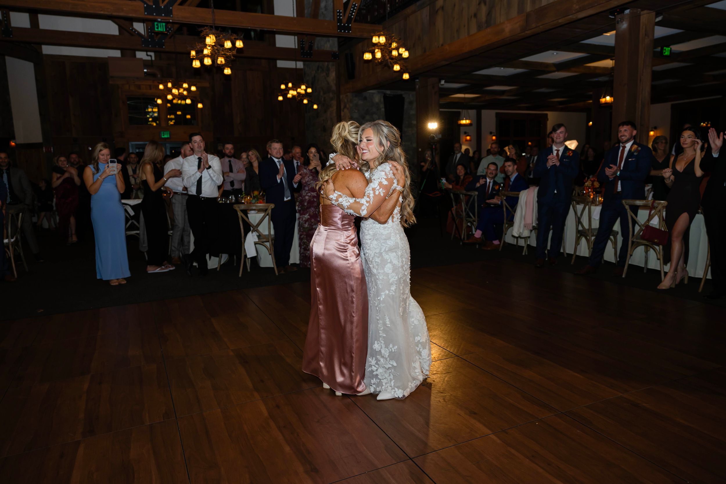 Wedding reception dance floor with guests celebrating in a dimly lit ballroom setting.