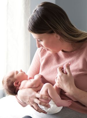 Mother holding her newborn baby during a lifestyle newborn photography session in Calgary, Alberta.