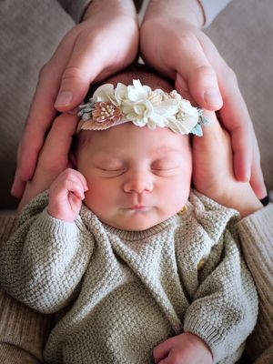 Image of a newborn baby whose head is being held by both parents during a cozy lifestyle newborn photography session in Calgary, Alberta.