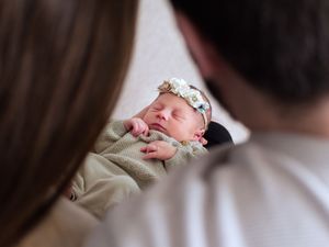 Image of newborn baby girl in Calgary. Baby is shown from the view between her parents two heads. Calgary Newborn Photographer.