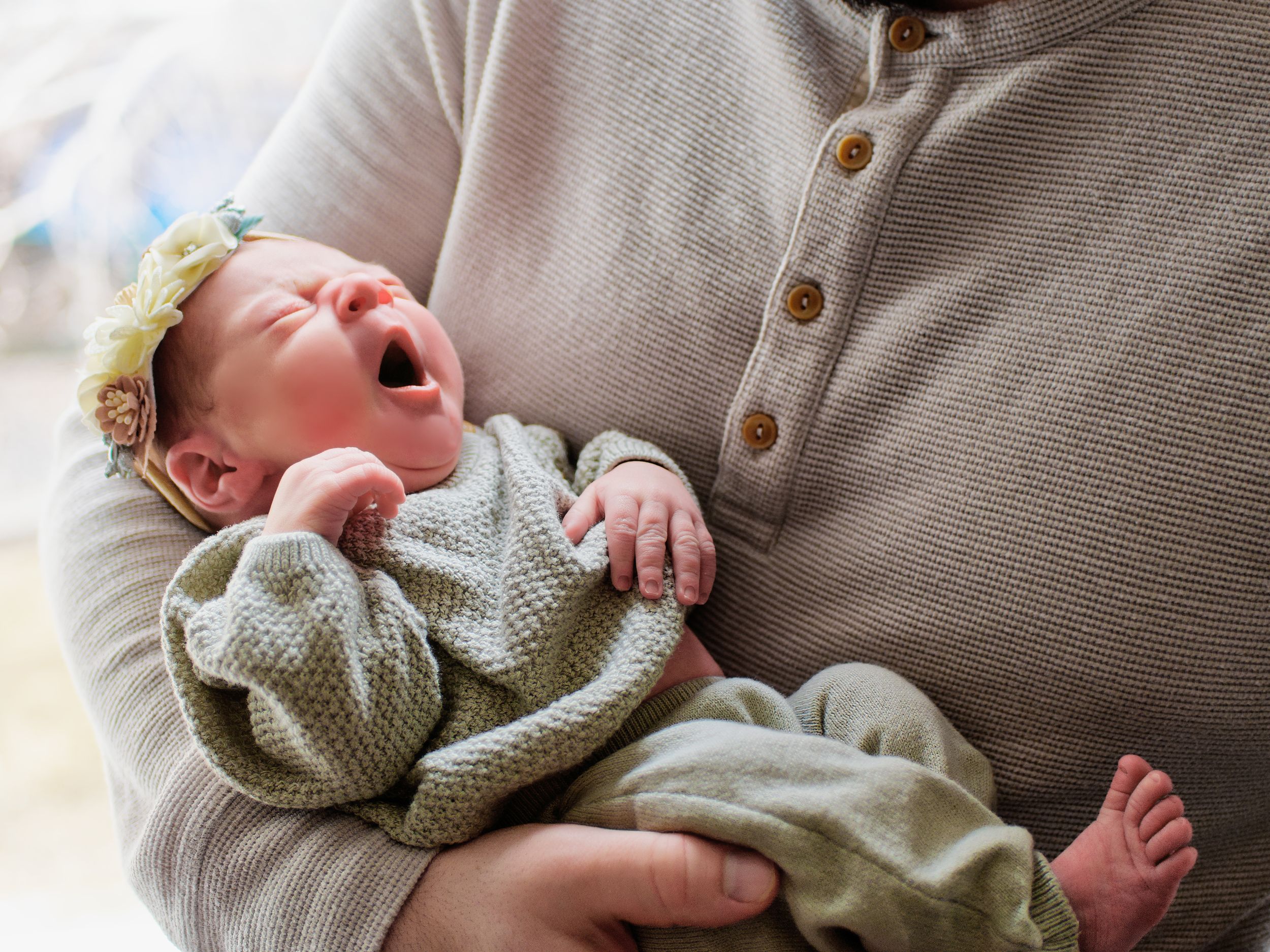 Newborn baby being held by parent during a cozy lifestyle newborn photography session in Calgary, Alberta.