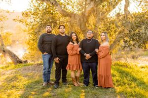 Group photo of family members standing together under golden autumn trees.