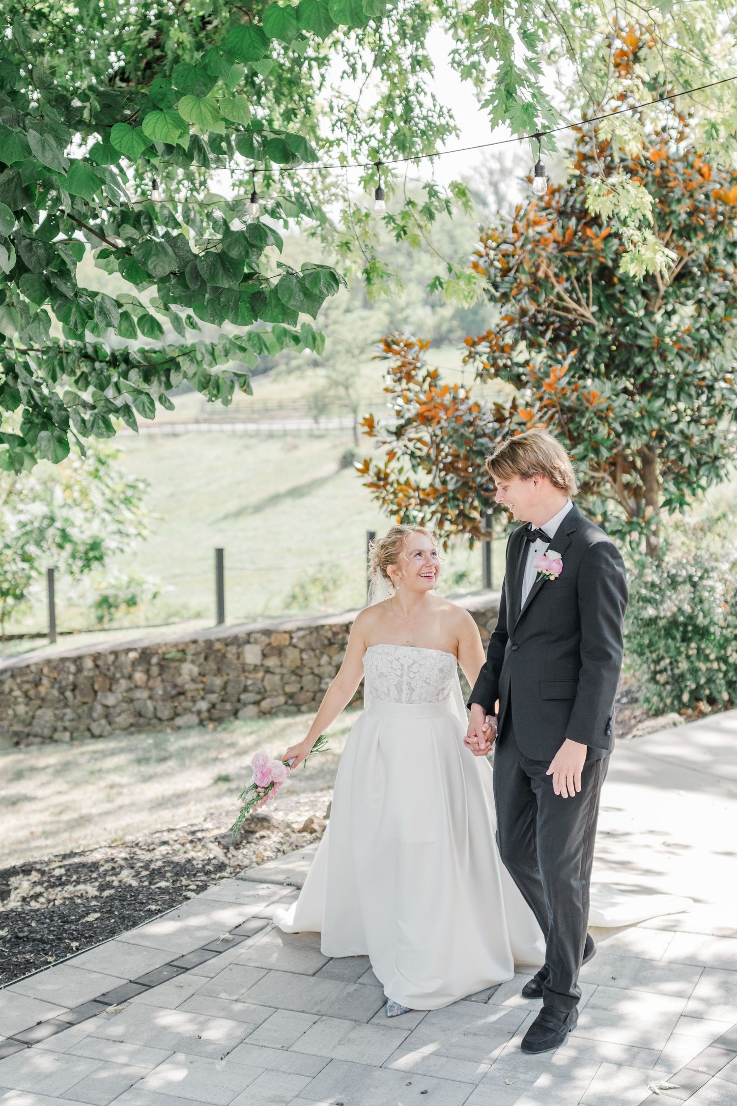 A light and airy wedding portrait on a stone path with greenery and rustic scenery.