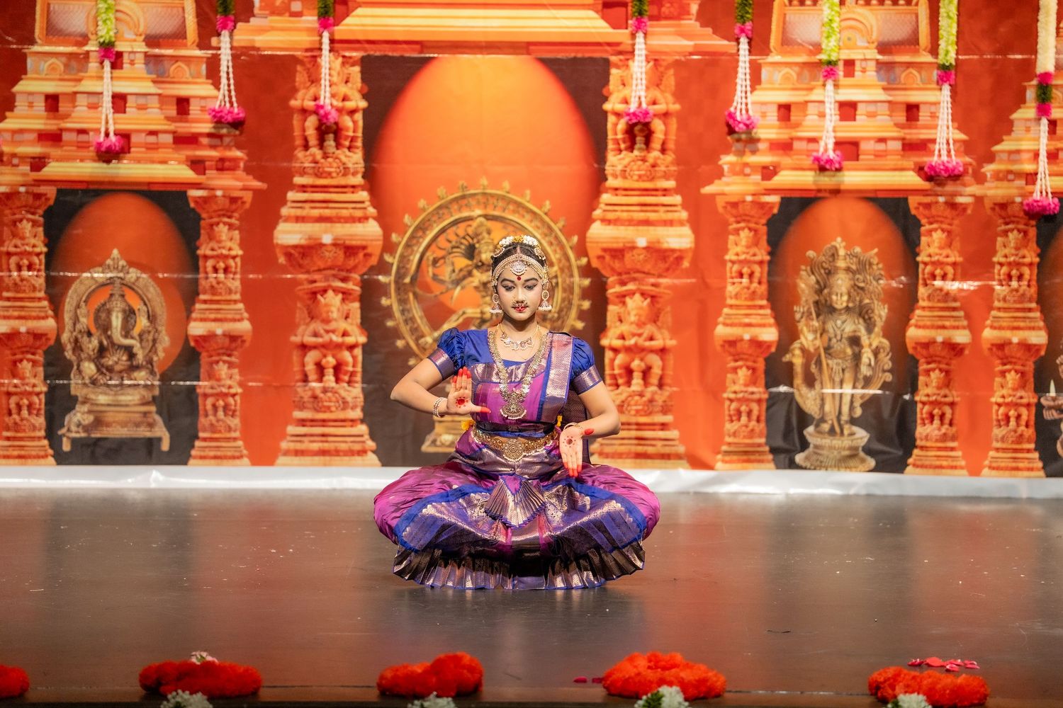 Traditional Indian dance performance in colorful costume against ornate temple backdrop with red and gold architecture.