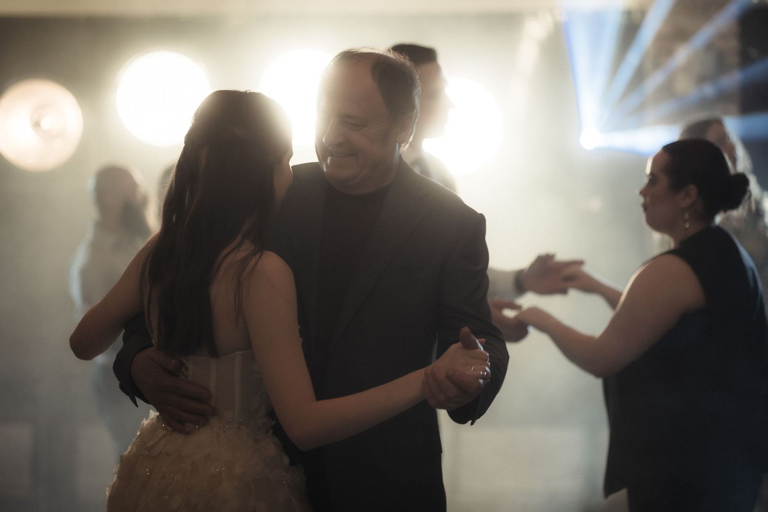 Couples slow dance together at an evening event with soft lighting and bokeh effects in the background.