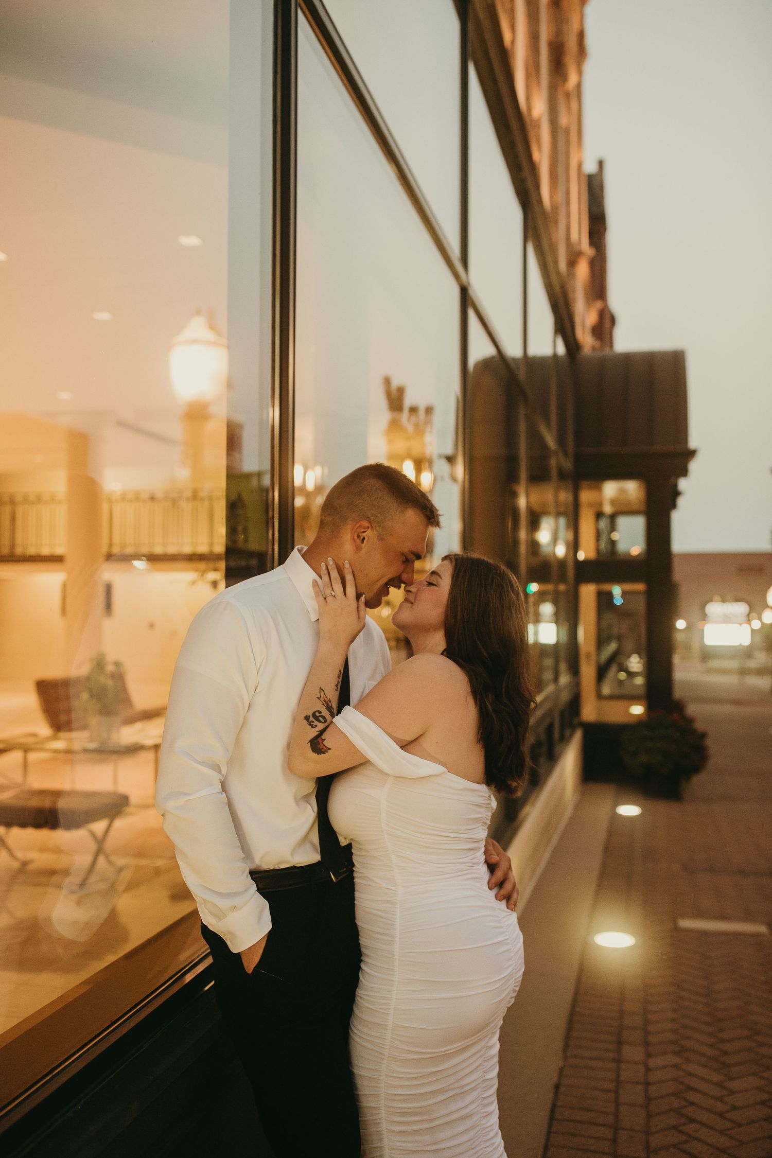 Couple lean up against the wall in Dubuque Iowa romantically holding each other.  The woman holds the man's face in a loving manner.