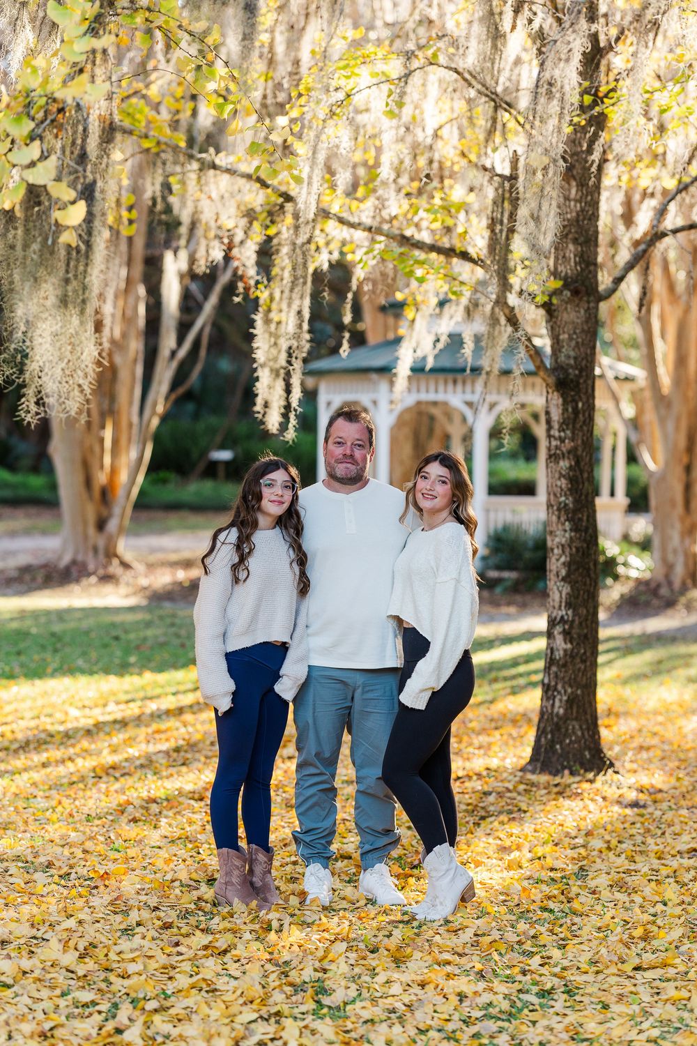 Family enjoying an autumn day together in a park with golden leaves scattered on the ground.