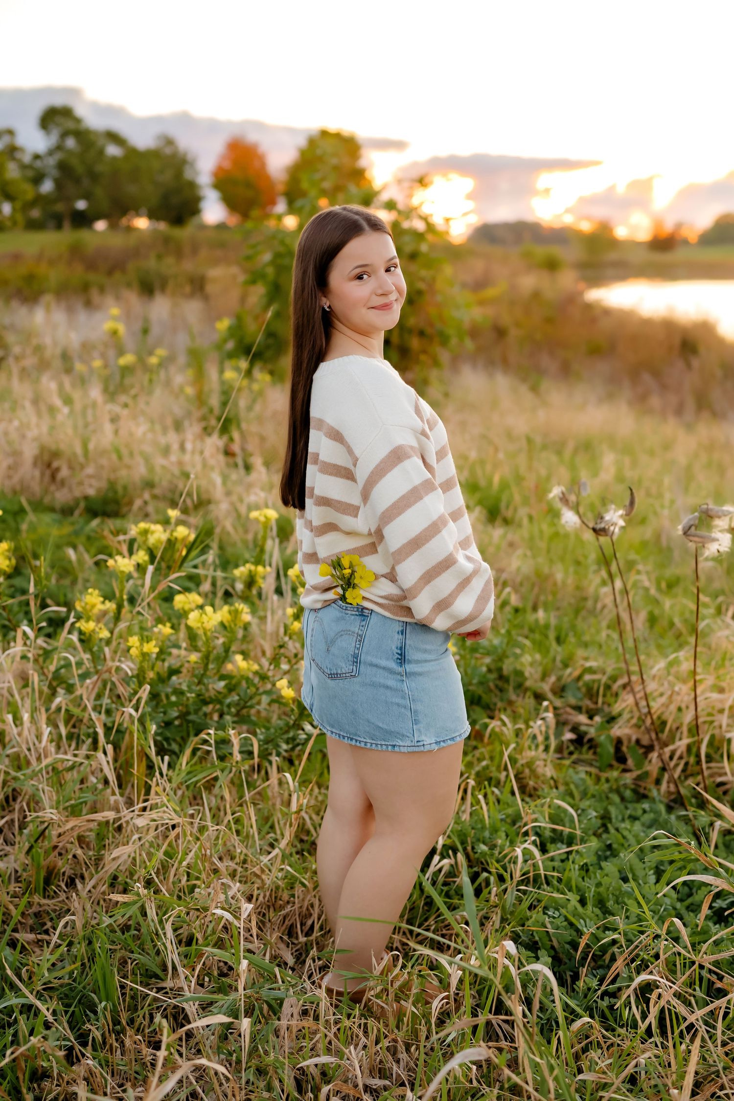 Casual autumn outdoor photoshoot in a wildflower field at sunset wearing a striped sweater and denim shorts.