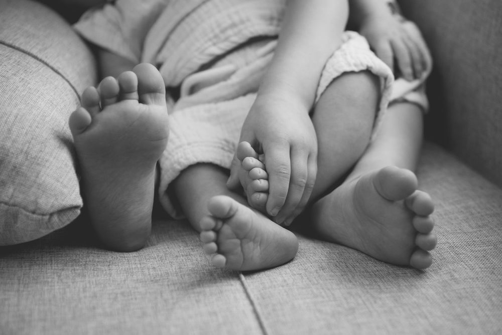 Black and white close-up of tiny baby feet on soft blanket.