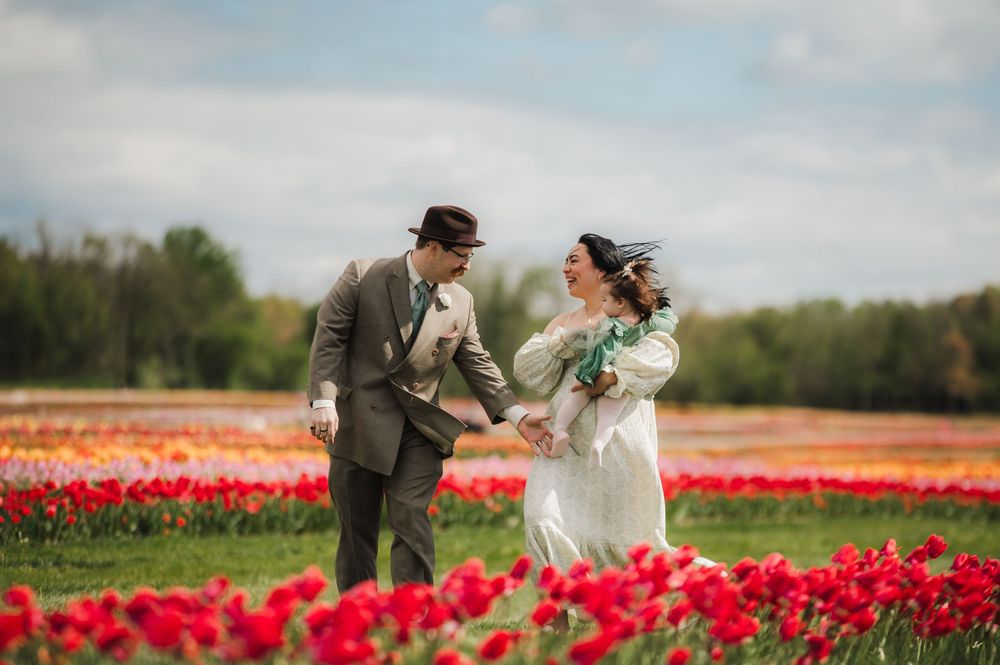 Couple shares intimate moment in field of bright red tulips during spring.