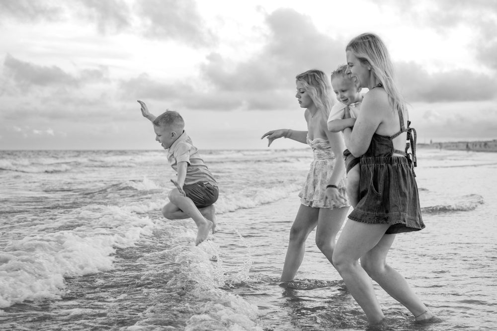 Group of friends playing and splashing in ocean waves at sunset.