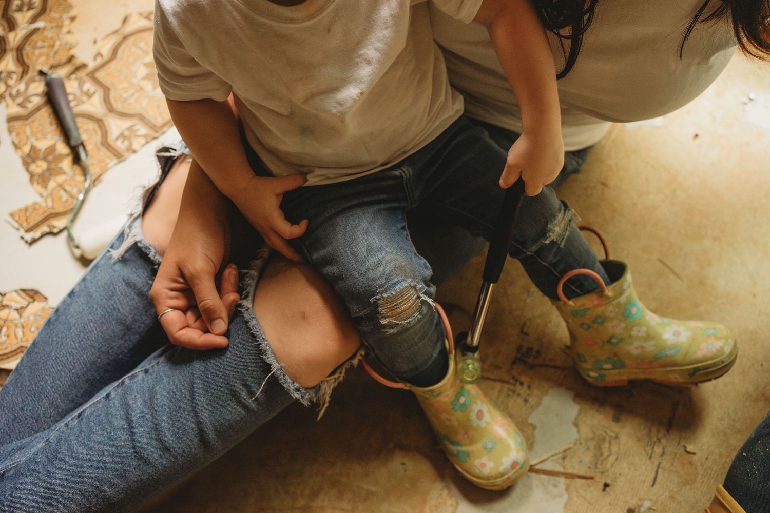 Close up of worn denim jeans and muddy work boots on floor.